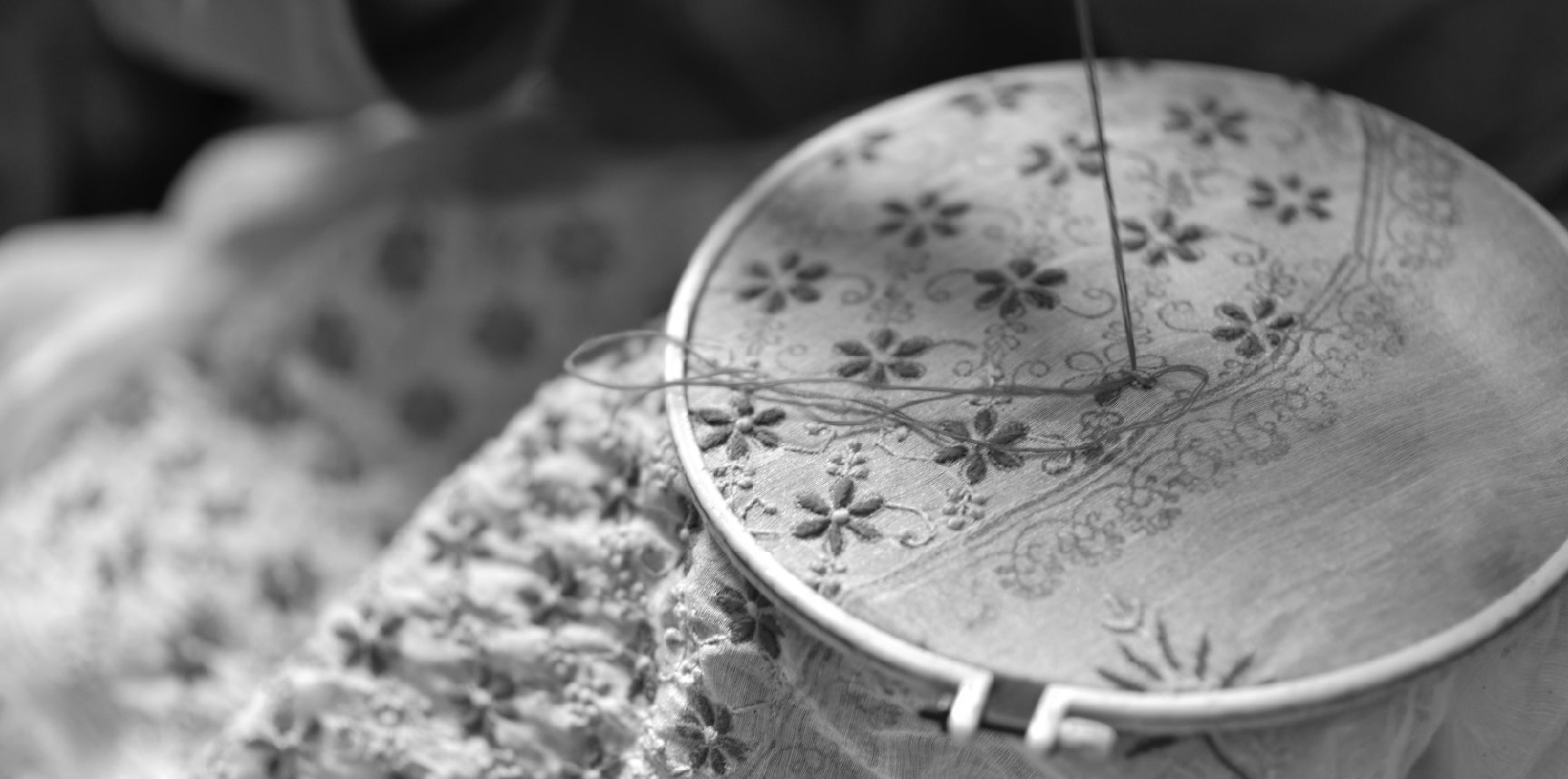 Broderie florale en cours sur un tambour à broder, aiguille et fil